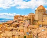Panoramica di Volterra, con le sue case in pietra e tetti in cotto, che si estende verso le colline toscane, ricordando la bellezza di San Gimignano.