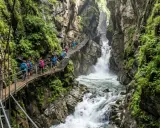 Sentiero sospeso tra le rocce e la vegetazione lussureggiante, con cascate fragorose che scendono nel **orrido di Bellano**.
