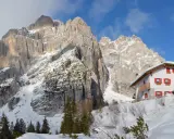 Rifugio alpino innevato ai piedi di maestose vette rocciose, un vero spettacolo di posti belli in montagna Veneto inverno.