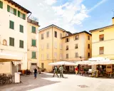 Piazza con edifici storici e tavolini all'aperto, ideale per scoprire cosa vedere a Pistoia in un giorno.