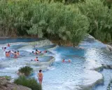Persone si rilassano nelle cascate naturali delle terme famose in Italia, circondate da vegetazione lussureggiante.