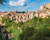 Un affascinante borgo toscano da visitare, arroccato su una rupe tufacea, con case in pietra e torri che si stagliano contro il cielo azzurro.