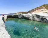 Un uomo nuota in acque cristalline tra scogliere bianche. Un luogo ideale per scoprire le spiagge di Bosa e cosa vedere.