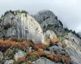 Val di Mello: maestose rocce grigie e boschi autunnali dai colori caldi, un paesaggio mozzafiato da scoprire.