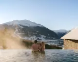 Coppia in una piscina termale con vista sulle montagne innevate. Un'oasi di relax, perfetta per chi cerca terme vicino Milano.