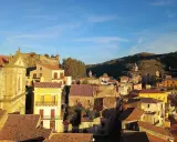 Panoramica di Castiglione di Sicilia al tramonto, con case dai tetti rossi e un castello in rovina su una collina.