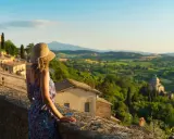Donna con cappello ammira il panorama collinare toscano, perfetto per scoprire cosa visitare in Toscana in 2 giorni.
