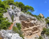 Scogliera rocciosa con una scalinata in mattoni che sale verso la cima, dove si intravede un rudere. Si immagina il **salto di Tiberio** da questo luogo suggestivo.