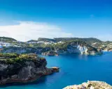Panoramica della **cala dell'acqua a Ponza**, con case colorate aggrappate alla collina e un mare blu intenso.