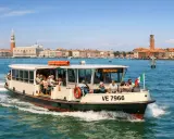 Barca con passeggeri diretta a Murano, con Venezia sullo sfondo. Un modo semplice per capire come arrivare a Murano da Venezia.