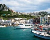 Barche nel porto di Capri, con la città arroccata sulla collina. Un ottimo punto di partenza per capire come raggiungere Capri da Napoli.