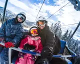 Famiglia felice in seggiovia, pronta per sciare. Ottima meta per chi cerca dove andare a sciare vicino Milano.