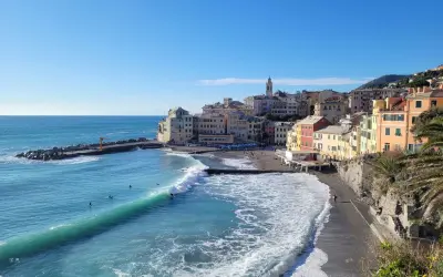Colorati borghi medievali vicino a Genova, con onde turchesi che si infrangono sulla spiaggia di ciottoli.