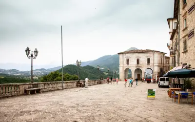 Piazza di Civitella del Tronto con edifici storici, gente che passeggia e vista panoramica sulle colline verdi.