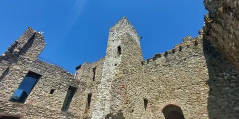 Rovine di un castello nel centro storico di Passignano sul Trasimeno, con mura in pietra e cielo azzurro.