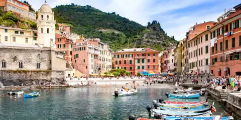Vernazza cosa vedere: colorate case a picco sul mare, la torre campanaria e barche ormeggiate nella baia. Un incanto ligure.