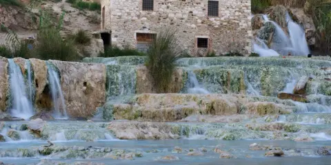 Cascate termali naturali con un antico mulino in pietra, un'oasi di benessere nel cuore delle terme centro Italia.