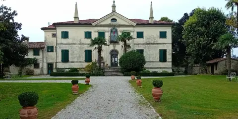 Villa storica con viale di ghiaia e vasi decorativi. Un luogo incantevole per scoprire cosa vedere a Clauiano.