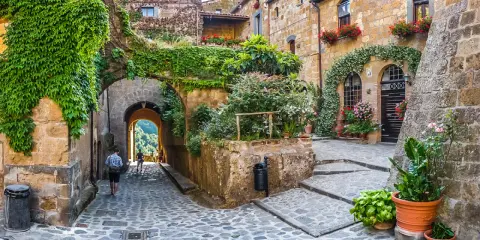 Un vicolo fiorito in uno dei 10 borghi più belli d'Italia, con archi coperti di edera e scorci panoramici.