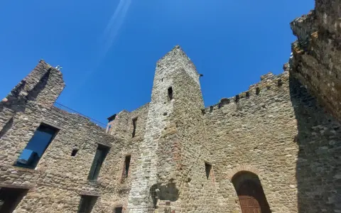 Rovine di un castello nel centro storico di Passignano sul Trasimeno, con mura in pietra e cielo azzurro.