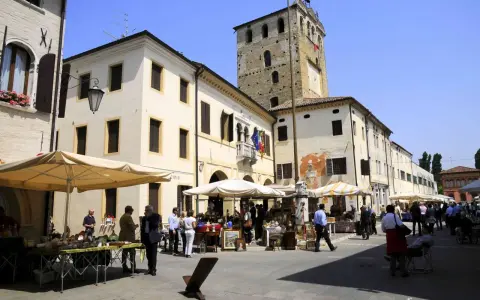 Mercato in piazza a Portobuffolè cosa vedere: bancarelle di antiquariato e la torre civica sullo sfondo.