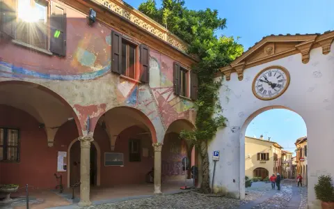 Un angolo suggestivo tra i borghi da visitare in Romagna. Archi affrescati, un portale con orologio e un vicolo acciottolato invitano alla scoperta.