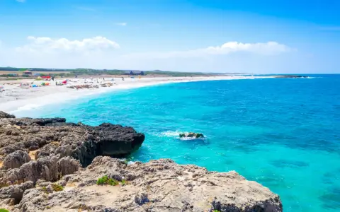 Scogli vulcanici e sabbia bianca su una spiaggia pop corn in Sardegna, con acque turchesi cristalline.