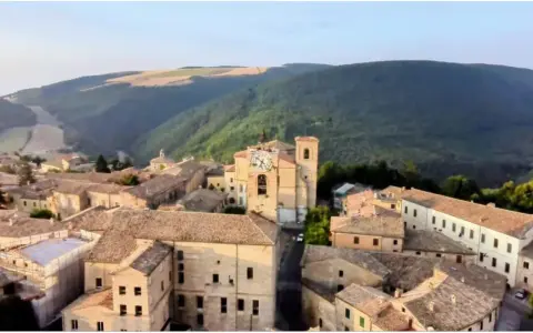 Borgo con torre dell'orologio, immerso nel verde delle colline. Chissà se è questo il borgo dei borghi vincitore.