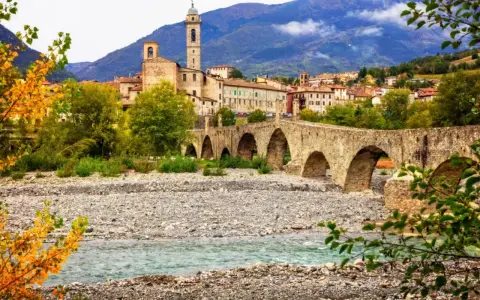 Ponte Gobbo a Bobbio, borgo dei borghi, con il fiume e le montagne sullo sfondo.