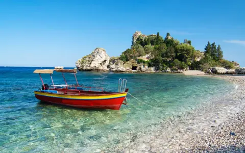 Barca rossa e gialla in acque cristalline, con isolotto verdeggiante sullo sfondo. Un angolo di paradiso che ricorda la bellezza di Sicilia e Sardegna.