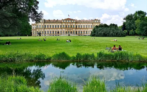 Villa Reale di Monza e il suo parco: un'idea per cosa vedere a Monza in un giorno. Persone rilassate sull'erba, un laghetto e il maestoso edificio.