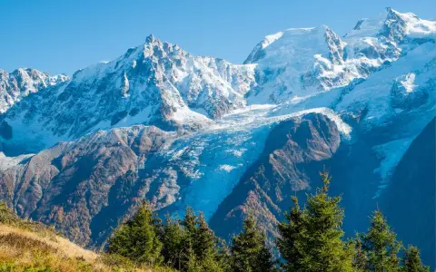 Ghiacciaio imponente tra le montagne italiane più famose, con cime innevate e boschi autunnali.