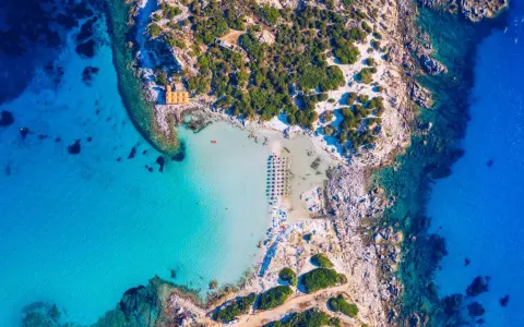 Spiaggia paradisiaca con acque cristalline, perfetta per itinerari Sardegna nord 7 giorni. Ombrelloni e lettini invitano al relax.