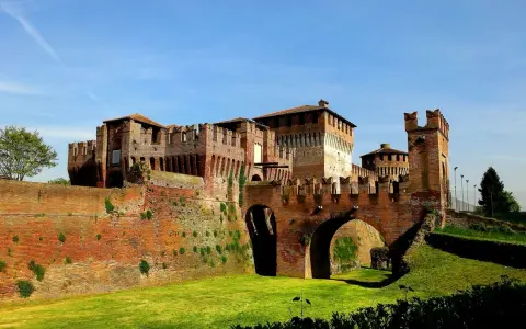 Castello Sforzesco, uno dei borghi belli vicino Cremona, con mura in mattoni rossi, ponti ad arco e fossato verde.