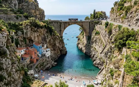 Un ponte ad arco domina un fiordo con case colorate aggrappate alla roccia. Il **furore costiera amalfitana** è un incanto tra mare turchese e sentieri scoscesi.