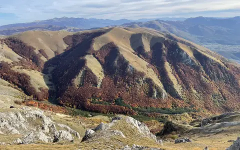 Autunno nel Val di Norcia, con montagne dolci e boschi dai colori caldi che scendono verso la valle.
