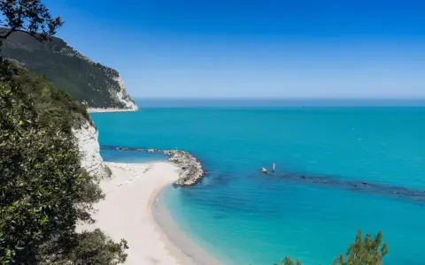 Spiagge piu belle d'Italia: una caletta di sabbia bianca incastonata tra scogliere a picco e un mare turchese cristallino.