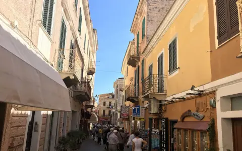 Passeggiata in un vicolo colorato, ideale per visitare La Maddalena in auto, con edifici storici e negozietti.