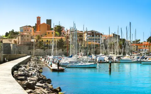 Porto turistico con barche a vela ormeggiate e case colorate che si affacciano sul mare, nel cuore del talamone centro storico.