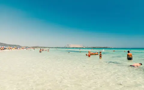 Acque cristalline e gente felice in spiaggia, forse qual è la parte più bella della Sardegna? Un paradiso azzurro.