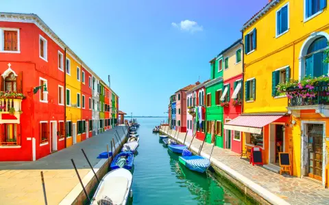 Colorate case affacciate su un canale con barche ormeggiate, un'incantevole scena di **Murano e Burano**.