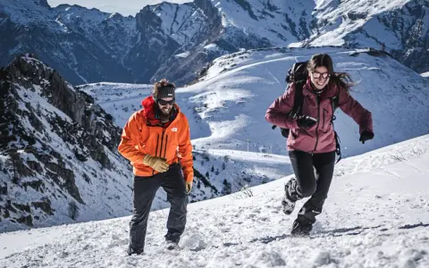 Coppia in montagna con abbigliamento da neve, godendosi l'estate in un paesaggio innevato.