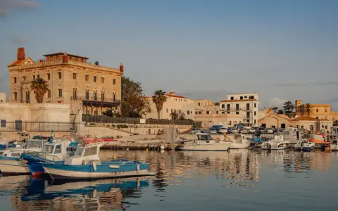 Porto di Favignana con barche ormeggiate e edifici storici. Per sapere come arrivare a Favignana, guarda questo porto!