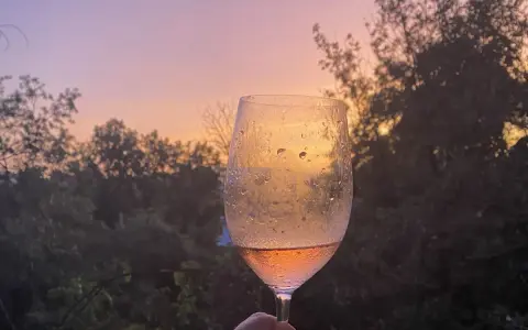 Un calice di vino rosato riflette il tramonto sulle dolci colline del Chianti.