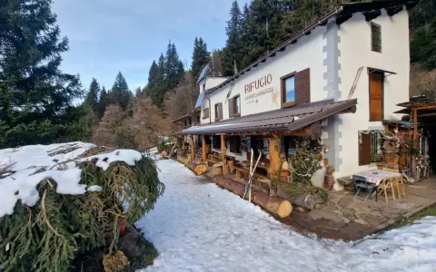 Rifugio Cimon della Bagazza, un luogo accogliente con rifugi aperti in inverno in Lombardia, circondato da neve e alberi.