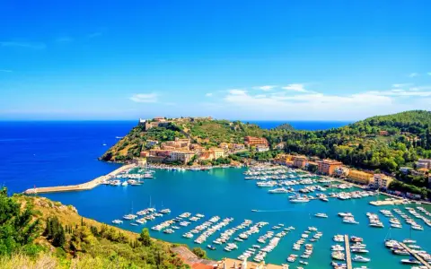 Porto Ercole, con le sue splendide spiagge e il porto pieno di barche, incanta sotto un cielo azzurro.