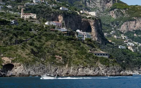 Un traghetto da Amalfi a Positano sfreccia nel mare blu, con case bianche aggrappate alle scogliere verdi.