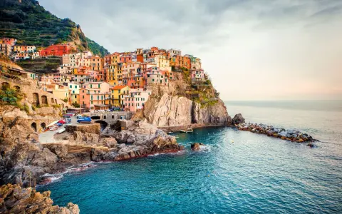 Manarola, uno dei borghi italiani da visitare, si aggrappa alla scogliera con le sue case colorate che si tuffano nel mare blu.