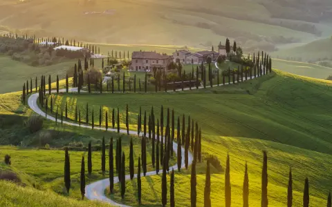 Un sogno per un tour Toscana 3 giorni: colline verdi, cipressi e un casale al tramonto.
