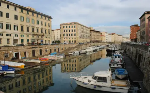 Canali e palazzi storici a Livorno, perfetti per gite di un giorno. Barche ormeggiate riflettono l'architettura.